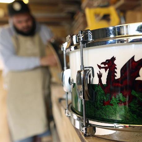 drum with red dragon on itwhile man in the background working in the drum studio
