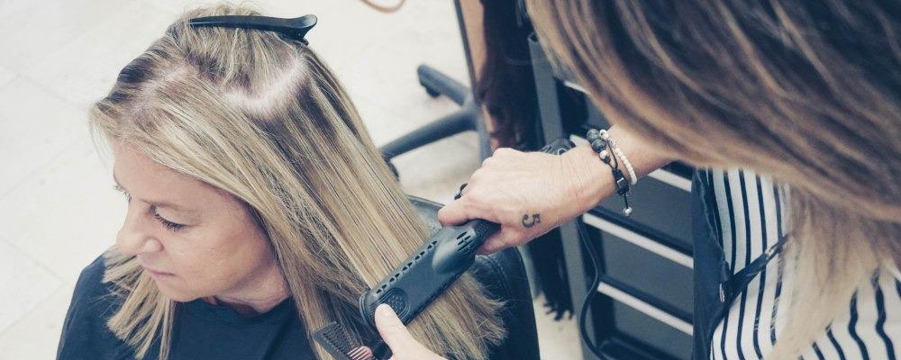 A hairdresser straightening a clients hair in a salon