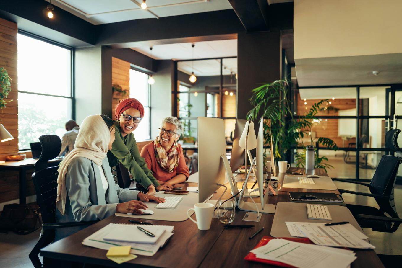 Three females sat in a relaxed modern office environment